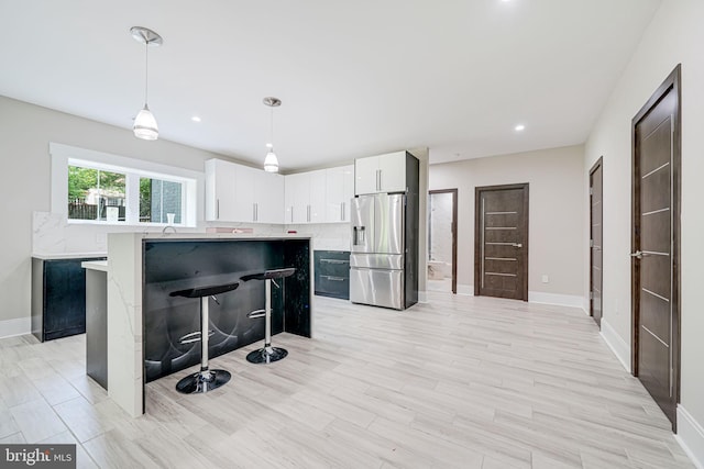 9908 Blake Ln, Oakton, VA 22124 - kitchen featuring stainless steel refrigerator with ice dispenser, light countertops, a breakfast bar area, white cabinets, and a kitchen island