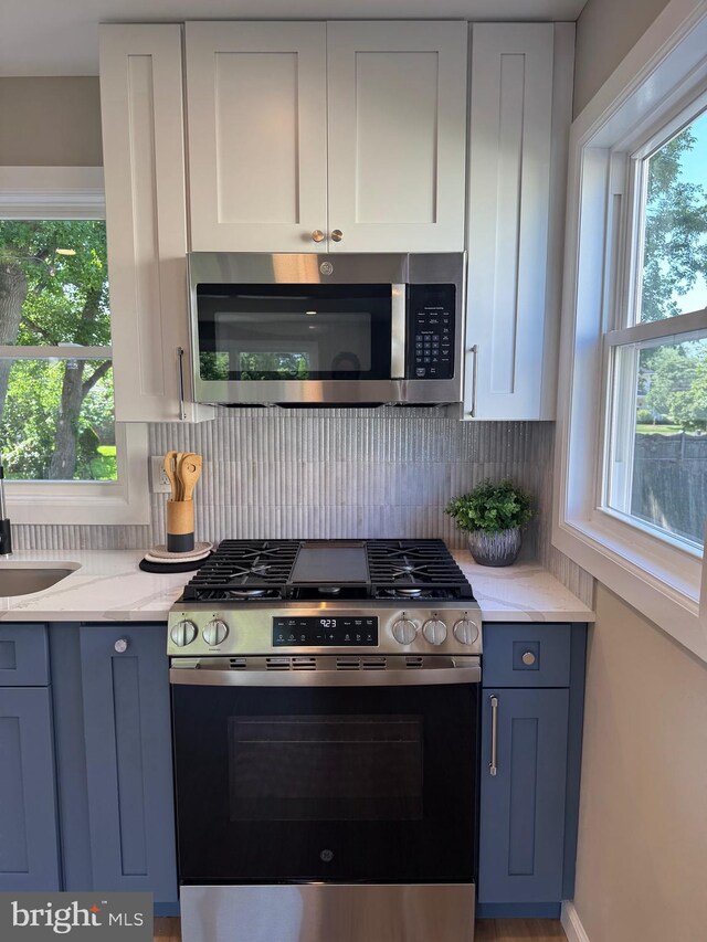 512 Majestic Ave, Bellmawr, NJ 08031 - kitchen featuring stainless steel appliances, backsplash, blue cabinetry, light stone countertops, and white cabinets