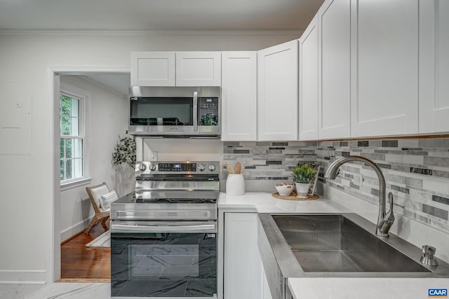 1623 Mason Ln, Charlottesville, VA 22903 - kitchen with appliances with stainless steel finishes, white cabinetry, tasteful backsplash, light countertops, and ornamental molding