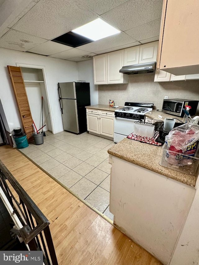 1618 S 6th St, Philadelphia, PA 19148 - kitchen featuring stainless steel appliances, under cabinet range hood, white cabinetry, a paneled ceiling, and light wood finished floors