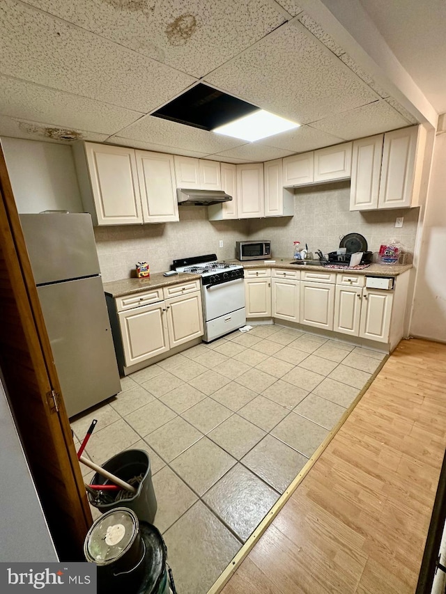 1618 S 6th St, Philadelphia, PA 19148 - kitchen with stainless steel appliances, under cabinet range hood, backsplash, a drop ceiling, and light tile patterned floors