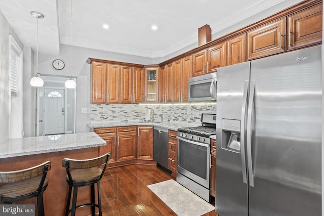3207 Salmon St, Philadelphia, PA 19134 - kitchen with stainless steel appliances, brown cabinetry, light stone counters, dark wood-style floors, and ornamental molding