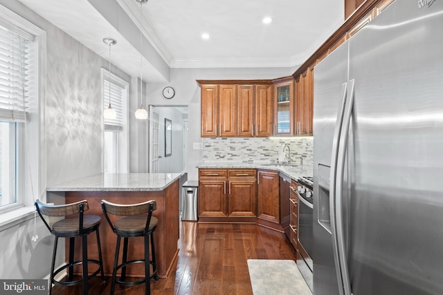 3207 Salmon St, Philadelphia, PA 19134 - kitchen featuring appliances with stainless steel finishes, brown cabinetry, light stone countertops, dark wood-style flooring, and glass insert cabinets