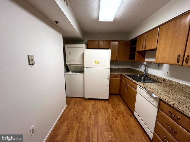 15100 Interlachen Dr Unit 4-701, Silver Spring, MD 20906 - kitchen with white appliances, stacked washer and clothes dryer, light wood-style flooring, brown cabinetry, and open shelves