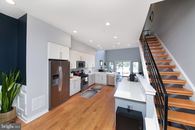 1318 E Eyre St, Philadelphia, PA 19125 - kitchen with appliances with stainless steel finishes, a peninsula, light countertops, light wood-style floors, and white cabinets