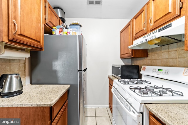1401 Kenny, Burlington, NJ 08016 - kitchen with white gas range oven, under cabinet range hood, brown cabinetry, decorative backsplash, and freestanding refrigerator