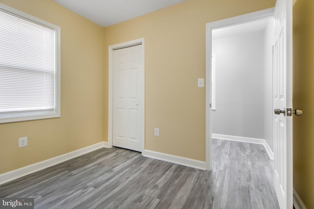 659 Charraway Rd, Baltimore, MD 21229 - unfurnished bedroom featuring wood finished floors, a closet, and multiple windows