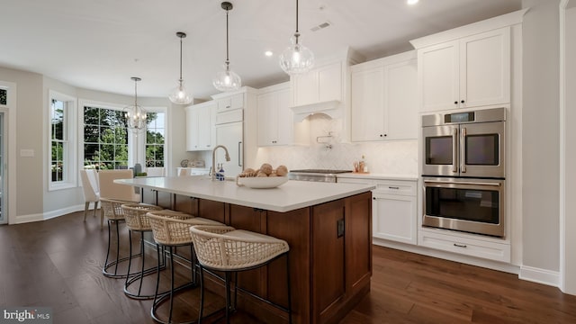 274 W Ashland St, Doylestown, PA 18901 - kitchen with double oven, decorative backsplash, a center island with sink, dark wood-type flooring, and light countertops