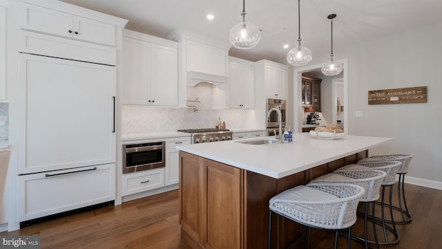 274 W Ashland St, Doylestown, PA 18901 - kitchen featuring paneled built in refrigerator, dark wood-style flooring, an island with sink, decorative backsplash, and light countertops