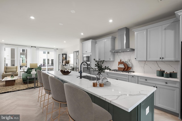 23079 Copper Tree Ter, Ashburn, VA 20148 - kitchen featuring wall chimney exhaust hood, appliances with stainless steel finishes, a kitchen bar, an island with sink, and recessed lighting