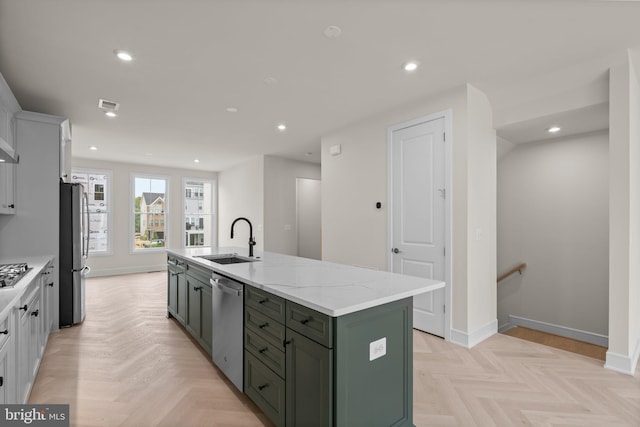 23079 Copper Tree Ter, Ashburn, VA 20148 - kitchen featuring green cabinets, appliances with stainless steel finishes, a kitchen island with sink, white cabinets, and light stone counters
