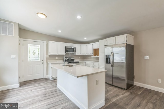 511 Sylvan Way, Pasadena, MD 21122 - kitchen with appliances with stainless steel finishes, light wood-style flooring, light countertops, white cabinets, and an island with sink
