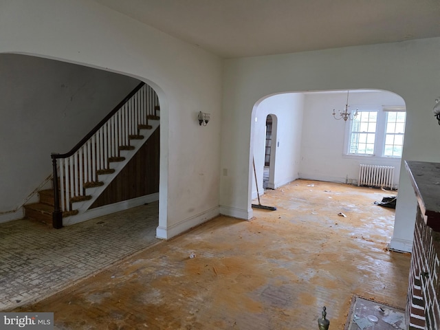 834 N Woodington Rd, Baltimore, MD 21229 - unfurnished living room featuring radiator, arched walkways, stairs, and a chandelier