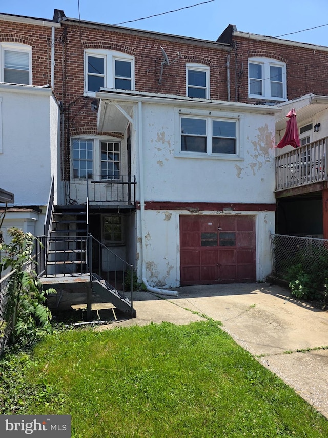 834 N Woodington Rd, Baltimore, MD 21229 - back of property with a garage, stairs, driveway, brick siding, and stucco siding