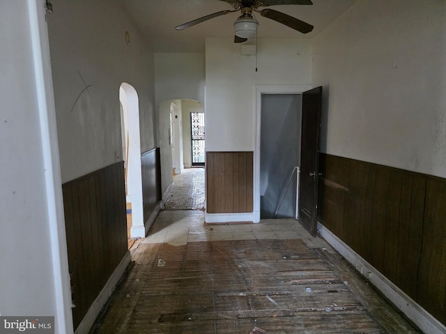 834 N Woodington Rd, Baltimore, MD 21229 - spare room with wainscoting, arched walkways, a ceiling fan, and wood walls