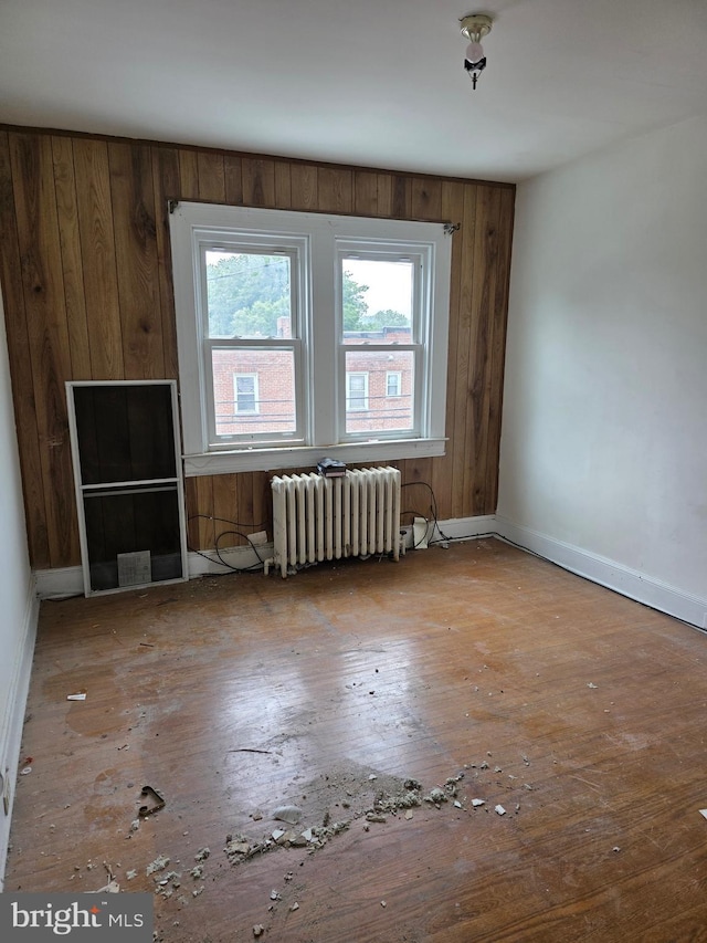 834 N Woodington Rd, Baltimore, MD 21229 - empty room featuring radiator heating unit, hardwood / wood-style flooring, and wood walls