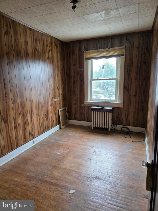 834 N Woodington Rd, Baltimore, MD 21229 - unfurnished room featuring radiator, wood walls, and wood finished floors