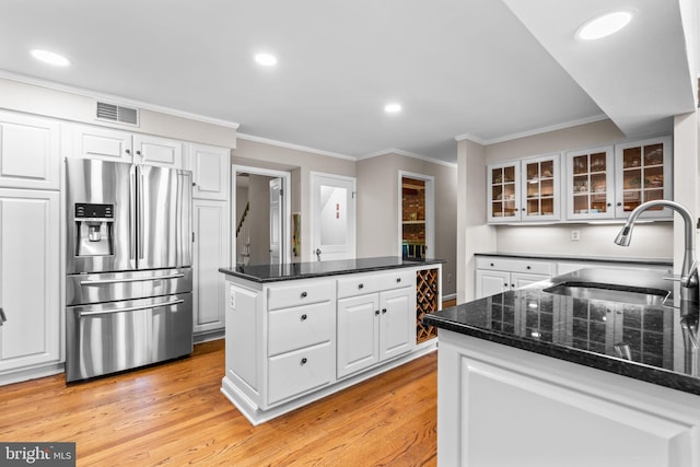 3773 Plum Hill Ct, Ellicott City, MD 21042 - kitchen with stainless steel fridge, white cabinetry, light wood-style flooring, ornamental molding, and glass insert cabinets