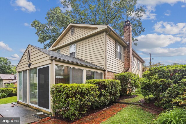 1606 Peacock Ln, Silver Spring, MD 20904 - view of home's exterior with a sunroom, a chimney, and brick siding
