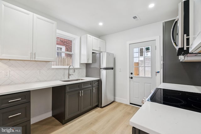 1835 Dudley St, Philadelphia, PA 19145 - kitchen featuring stainless steel appliances, light wood-style floors, white cabinets, light countertops, and tasteful backsplash
