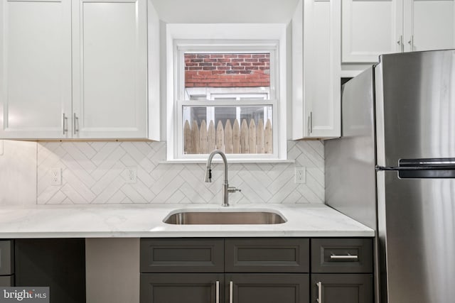1835 Dudley St, Philadelphia, PA 19145 - kitchen featuring freestanding refrigerator, tasteful backsplash, light stone countertops, and white cabinetry