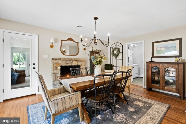 126 Woodview Dr, Doylestown, PA 18901 - dining area with wood finished floors, a chandelier, and a stone fireplace