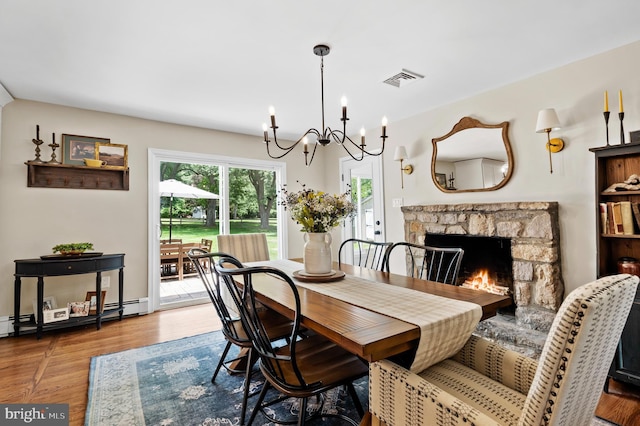 126 Woodview Dr, Doylestown, PA 18901 - dining room with a chandelier, a stone fireplace, wood finished floors, and a baseboard heating unit