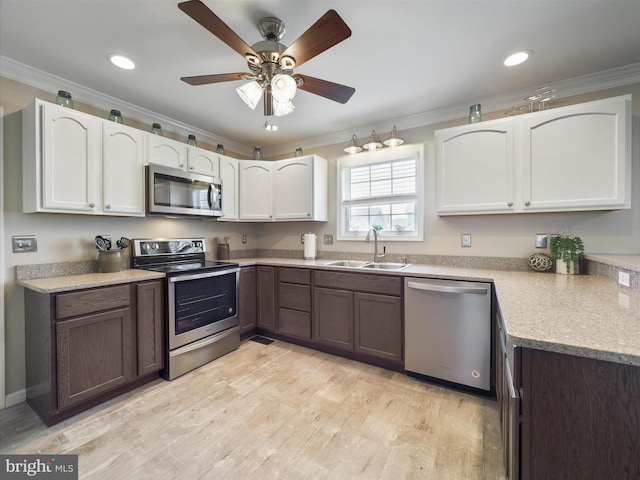 101 Carrera Ct, Inwood, WV 25428 - kitchen with appliances with stainless steel finishes, ornamental molding, white cabinetry, light wood-style flooring, and a ceiling fan