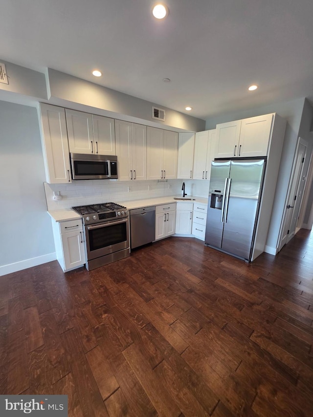 1101 Fern St NW Unit 301, Washington, DC 20012 - kitchen with appliances with stainless steel finishes, dark wood-type flooring, light countertops, white cabinets, and recessed lighting