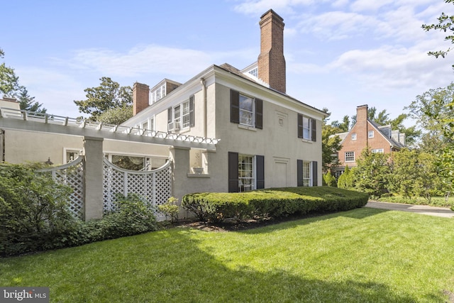 4332 N Charles St, Baltimore, MD 21218 - rear view of house featuring a chimney, stucco siding, and a yard