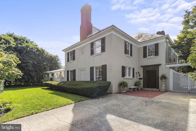 4332 N Charles St, Baltimore, MD 21218 - view of front of home with stucco siding, a chimney, a front lawn, and a patio