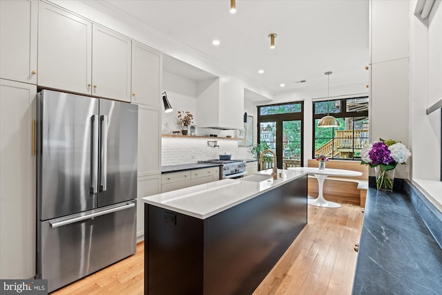 7 U St NW, Washington, DC 20001 - kitchen featuring high quality appliances, light wood-type flooring, an island with sink, ornamental molding, and decorative backsplash