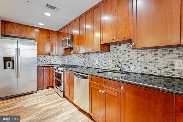 3650 S Glebe Rd Unit 239, Arlington, VA 22202 - kitchen featuring appliances with stainless steel finishes, dark stone countertops, brown cabinetry, light wood-style floors, and recessed lighting
