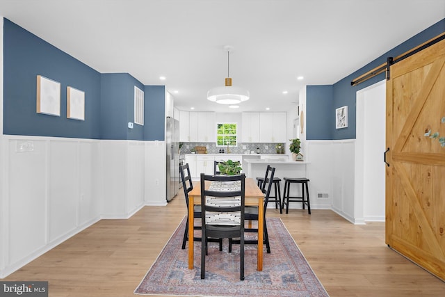 2910 Georgia Ave, Halethorpe, MD 21227 - dining room with a barn door, light wood-style floors, a wainscoted wall, a decorative wall, and recessed lighting