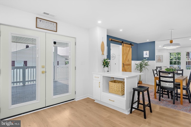 2910 Georgia Ave, Halethorpe, MD 21227 - kitchen with french doors, a barn door, light wood-type flooring, light countertops, and decorative light fixtures