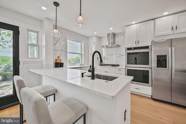 1539 K St SE, Washington, DC 20003 - kitchen with appliances with stainless steel finishes, wall chimney range hood, white cabinets, healthy amount of natural light, and recessed lighting
