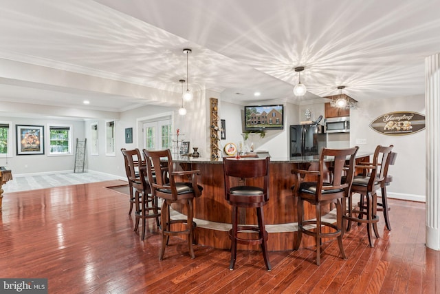1508 Cornerstone Ct, Crownsville, MD 21032 - indoor wet bar featuring freestanding refrigerator, stainless steel microwave, wood-type flooring, crown molding, and pendant lighting
