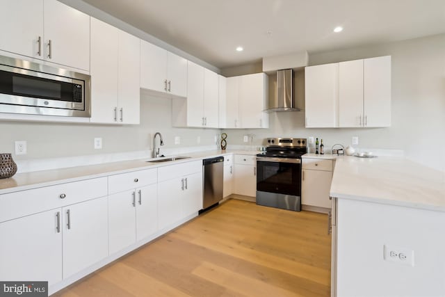 4900 D St SE, Washington, DC 20019 - kitchen with stainless steel appliances, wall chimney exhaust hood, light wood finished floors, light countertops, and recessed lighting