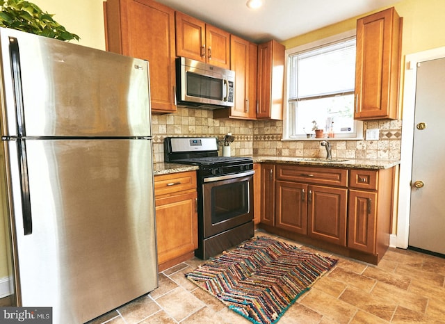 2426 E Indiana Ave, Philadelphia, PA 19134 - kitchen with appliances with stainless steel finishes, decorative backsplash, brown cabinetry, and light stone countertops