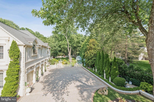 423 Seneca Rd, Great Falls, VA 22066 - view of patio / terrace featuring decorative driveway, a garage, and view of wooded area
