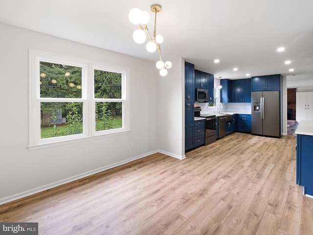 110 Wembley Rd, Wilmington, DE 19808 - kitchen featuring stainless steel appliances, blue cabinets, light countertops, light wood finished floors, and decorative light fixtures