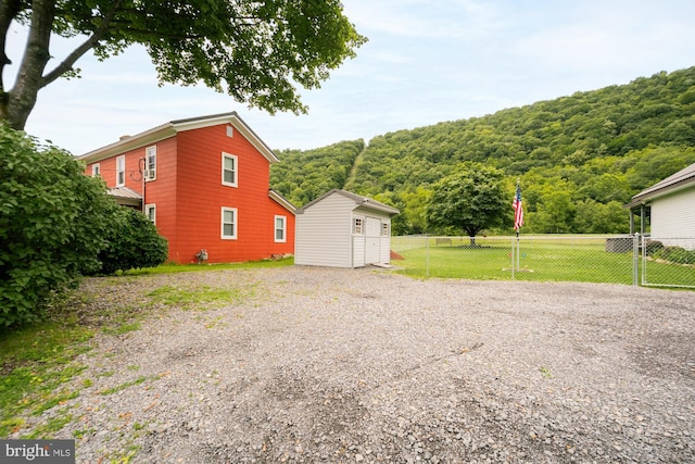 108 W Center St, Kitzmiller, MD 21538 - view of side of property featuring a storage shed, a wooded view, and gravel driveway