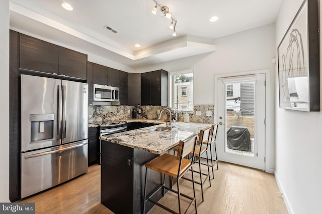 2228 Carpenter St, Philadelphia, PA 19146 - kitchen featuring stainless steel appliances, a kitchen breakfast bar, light wood-style flooring, tasteful backsplash, and light stone countertops