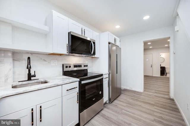 1354 Green St, Reading, PA 19604 - kitchen with appliances with stainless steel finishes, open shelves, white cabinetry, backsplash, and light wood-style floors