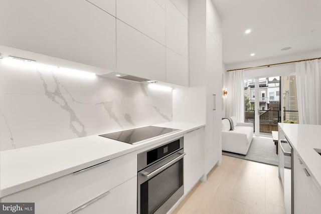 146 S St NW Unit B, Washington, DC 20001 - kitchen featuring oven, modern cabinets, black electric stovetop, white cabinets, and light wood-type flooring