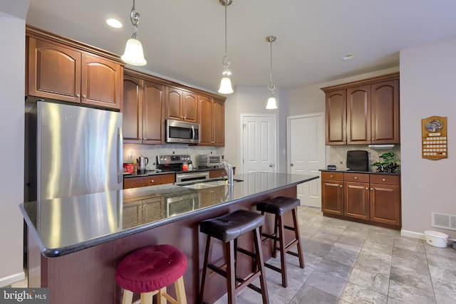 36 Elm Ct, Lancaster, PA 17603 - kitchen featuring stainless steel appliances, tasteful backsplash, a breakfast bar area, a kitchen island with sink, and decorative light fixtures
