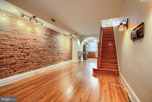 511 S Belnord Ave, Baltimore, MD 21224 - unfurnished living room featuring arched walkways, light wood-style floors, stairs, and rail lighting
