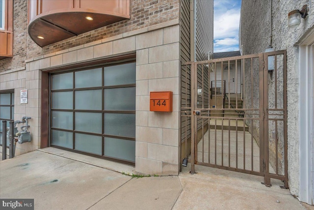 144 Levering St, Philadelphia, PA 19127 - doorway to property featuring concrete driveway, a garage, brick siding, and a gate