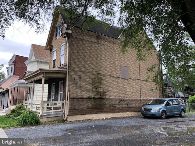 2450 N 6th St, Harrisburg, PA 17110 - view of side of home featuring a porch, brick siding, and a shingled roof