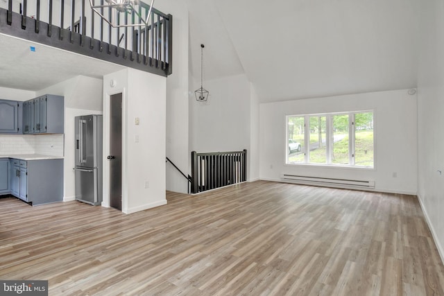 121 Almond Ct, Milford, PA 18337 - unfurnished living room with high vaulted ceiling, a baseboard heating unit, and light wood-type flooring